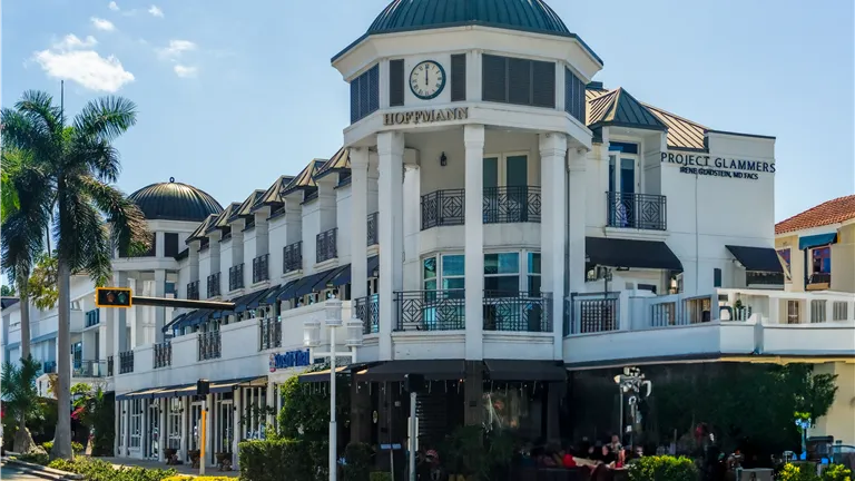 Elegant architecture at a shopping center in Naples, Florida with palm trees and clear skies.